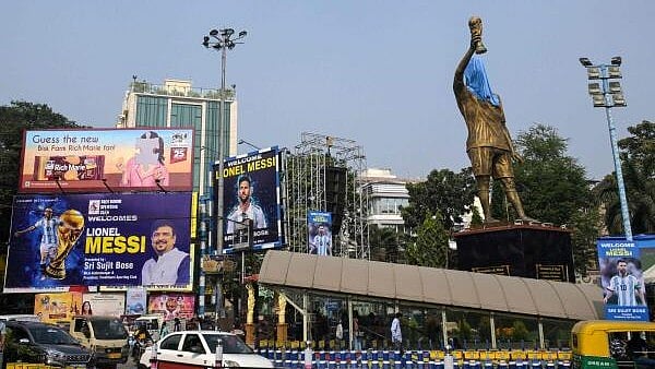 <div class="paragraphs"><p>Commuters cross promotional posters and veiled statue of Lionel Messi, on the eve of his visit, in Kolkata.</p></div>