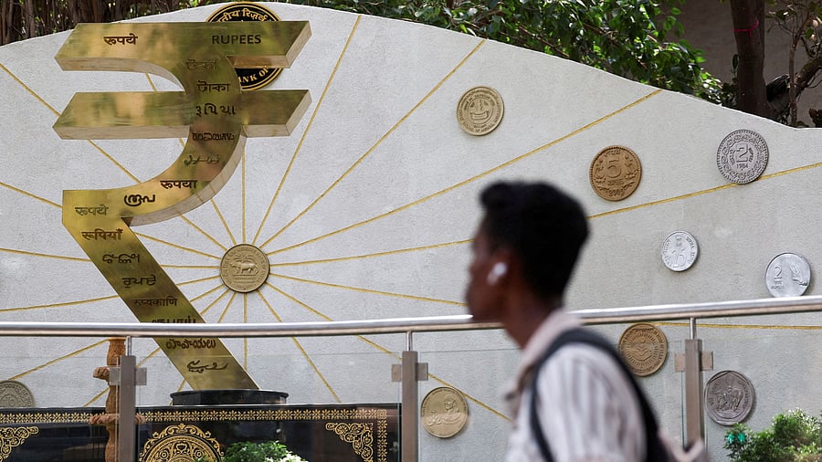 <div class="paragraphs"><p> A man walks past an installation of the Rupee logo and Indian currency coins outside the Reserve Bank of India (RBI) headquarters in Mumbai</p></div>