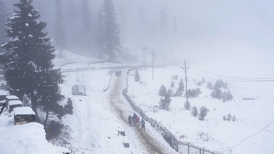 <div class="paragraphs"><p>People walk through a snow-covered road at Gulmarg in Baramulla district of North Kashmir.</p></div>