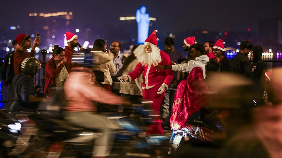 <div class="paragraphs"><p>A man dressed in a Santa Claus costume distributes candies and gifts to pedestrians and passersby, while children and adults wearing Santa hats gather at Tank Bund ahead of the Christmas festival, in Hyderabad.</p></div>