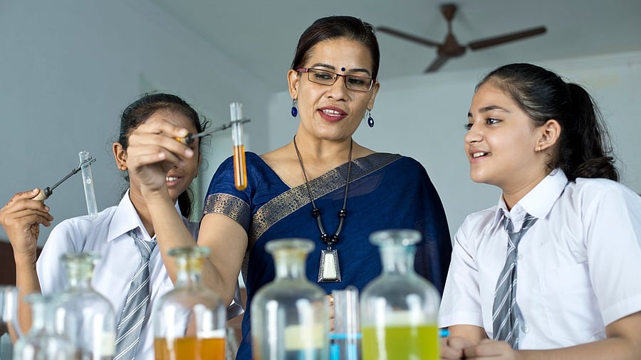 <div class="paragraphs"><p>Teacher assisting students doing chemical experiment in laboratory at school STEM education.</p></div>
