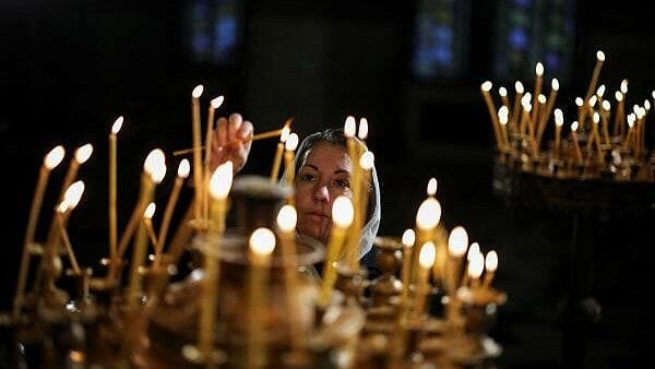 <div class="paragraphs"><p>A woman lights a candle as she attends a Mass on Christmas Day</p></div>