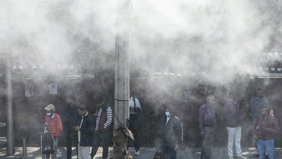 <div class="paragraphs"><p>Commuters stand amidst water being sprayed to curb air pollution, in New Delhi.</p></div>