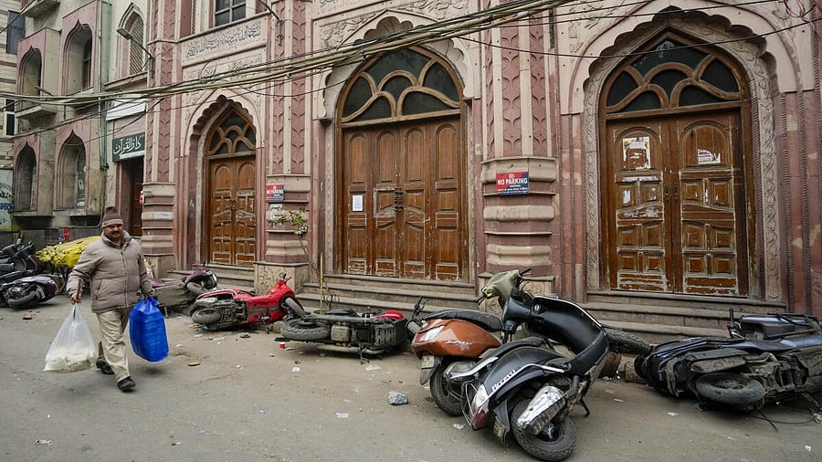 <div class="paragraphs"><p>A man walks past several two-wheeler lying on a roadside after violence erupted during a demolition drive of alleged encroachments from a land adjoining the Syed Faiz Elahi mosque and a nearby graveyard carried out by the Municipal Corporation of Delhi (MCD), at Turkman Gate area, in New Delhi.</p></div>