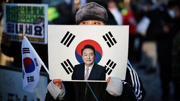 <div class="paragraphs"><p>A woman holds a sign bearing South Korean national flag with a portrait of former President Yoon Suk Yeol</p></div>