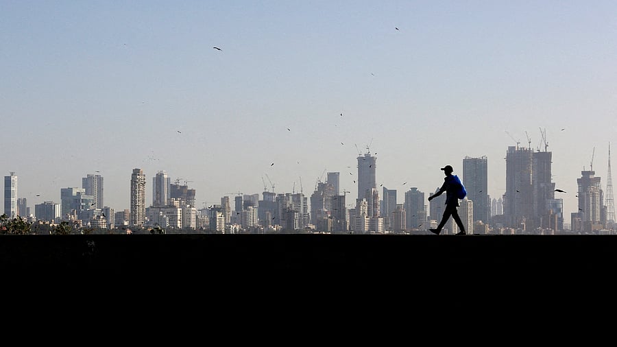 <div class="paragraphs"><p> A man walks along a wall overlooking central Mumbai's financial district skyline</p></div>