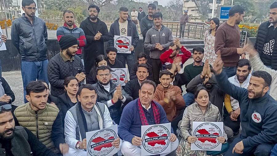 <div class="paragraphs"><p>BJP MLA and Leader of Opposition Sunil Sharma, center, along with party workers, sits on a dharna in support of Jammu University students demanding the establishment of a National Law University (NLU), in Jammu.</p></div>