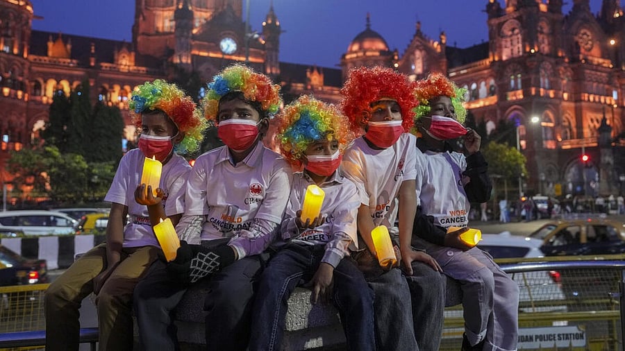 <div class="paragraphs"><p>Children wearing colourful wigs and face masks hold candles near the Chhatrapati Shivaji Maharaj Terminus, illuminated on the eve of World Cancer Day, in Mumbai.</p></div>