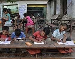 Children attend a school set up on a footpath in Ahmedabad on Friday, April 2, 2010. The footpath school is run by 62-year-old Kamal Parmar who started giving evening classes to children, mostly from slum areas, more than ten years ago. AP