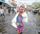 A woman carries a load as she wades through a flooded street after heavy rains in Visakhapatnam on Thursday. Reuters
