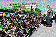Tourists look at padlocks (locks of love) attached to the Archeveche bridge in Paris. AFP