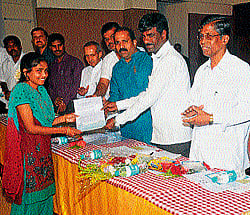 Minister for Ports, Inland Water Transport and Muzrai Kota Srinivas Poojary handing over a cheque to a beneficiary in Manipal on Monday. dh photo