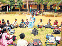 Caterpillars forced these students and teacher to continue with their classes at the open ground at government higher primary school at Shivalli village in Mandya taluk. dh photo