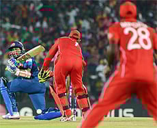 Sri Lankan cricketer Tillakaratne Dilshan (L) is watched by Zimbabwe wicketkeeper Brendan Taylor (C) as he plays a shot during an ICC Twenty20 Cricket World Cup match between Sri Lanka and Zimbabwe at The Mahinda Rajapaksa International Cricket Stadium in Hambantota on September 18, 2012. AFP PHOTO