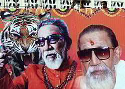 An onlooker is seen behind a poster bearing portraits of ailing right-wing Hindu party Shiv Sena supremo Bal Thackeray, erected near his residence in Mumbai on November 15, 2012. Mumbai police stepped up security November 15 to prevent any unrest as Indian firebrand politician Bal Thackeray was reported to be in critical condition at his home in the city. Large crowds of supporters gathered overnight outside the residence of the 86-year-old, who founded the right-wing Hindu party Shiv Sena and is widely accused of stoking ethnic and religious violence. AFP PHOTO