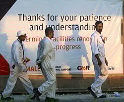 Workers walk past a banner at the international airport in Male, Maldives, Tuesday, Dec. 4, 2012. An airport deal to build and run a new terminal at Male airport, and to operate the entire airport for 25 years has been terminated amid a feud over political control of the Maldives. In 2010, under the government of former president Mohamed Nasheed, GMR Infrastructure and Malaysia Airports Holdings submitted the winning bid and took over the airport's operations from Maldives Airport Co. the same year. AP Photo