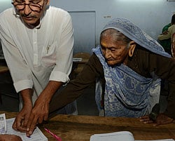 Elderly Indian voter Ujamben Kanjibhai Dudhatra (R), who according to voter identity documents is 106 years old, makes a thumb imprint as the completes formalities before casting her vote for state assembly elections in Ahmedabad on December 17, 2012. Millions of Indians are voting in the final stage of Gujarat state elections with Hindu nationalist Narendra Modi seeking a clear victory to bolster his prime ministerial ambitions in 2014. AFP PHOTO /