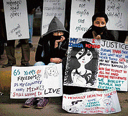 Protesters sit on a sidewalk with anti-rape placards in New Delhi on Sunday. AP