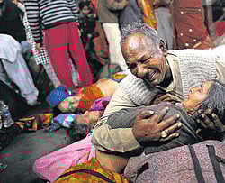 A man holds the body of his wife, killed in a stampede on a platform of the Allahabad railway station on Sunday. AP