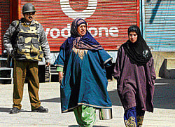 A paramilitary trooper keeps watch as Kashmiri women walk past during a curfew in downtown Srinagar on Wednesday. AFP