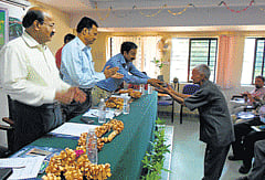 Forest College dean Dr N A Prakash hands over bamboo sapling to a Bamboo grower Ponnappa, at a seminar on bamboo cultivation held at Ponnampet Forest College in Gonikoppa. DH Photo