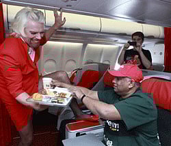 British entrepreneur Richard Branson, who wears an AirAsia stewardess uniform, serves AirAsia's Chief Executive Tony Fernandes during an AirAsia promotional event on a flight from Perth to Kuala Lumpur May 12, 2013. Branson shaved his legs and dressed up as a stewardess during a flight from Australia to Malaysia after losing a bet to his friend Fernandes, on which of their 2010 Formula One racing car teams would finish ahead of the other. AirAsia/Handout via Reuters