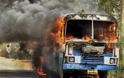 A torched bus is seen during a violent protest against opening of an ashram near Rohtak on Sunday. PTI Photo