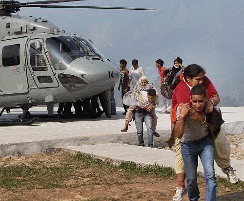 NDRF personnel carrying rescued pilgrims after they alighted from a chopper at Guptkashi in Uttarakhand on Friday. PTI Photo