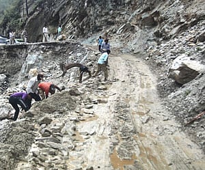 People clear road after landslide, in Gauchar on Monday.PTI Photo