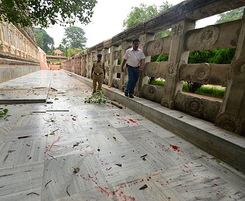 A security officer inspects the site of an explosion as blood lies splattered around the Bodhi tree, under which Buddha is believed to have achieved enlightenment, at the premise of the Mahabodhi Temple, the Buddhist Great Awakening temple, in Bodhgaya, about 130 kilometers (80 miles) south of Patna, the capital of the eastern Indian state of Bihar, Sunday, July 7, 2013. A series of small blasts hit three Buddhist temples in eastern India early Sunday, injuring at least two people, police said. (AP Photo