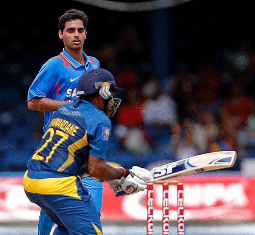 Bhuvneshwar Kumar, rear, looks at Sri Lanka opening batsman Mahela Jayawardene, who reacts after being caught by Ravichandran Ashwin for 22 runs, during the final match of the Tri-Nation cricket series in Port-of-Spain, Trinidad, Thursday, July 11, 2013. (AP Photo/