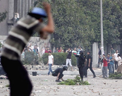 A supporter of deposed Egyptian President Mohamed Mursi tries to take cover as a police officer uses a shotgun during clashes in Nasr city area, east of Cairo July 27, 2013. At least 70 people died on Saturday after security forces attacked supporters of deposed President Mohamed Mursi in Cairo, Muslim Brotherhood spokesman Gehad El-Haddad said, adding the toll could be much higher. REUTERS