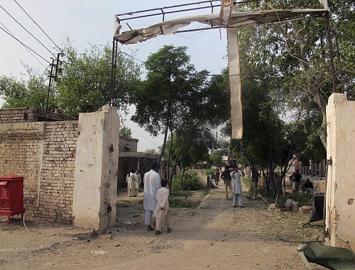 A plainclothes police officer takes a photo with his mobile phone of a damaged gate of center jail caused by Taliban militants attacked, Tuesday, July 30, 2013 in Dera Ismail Khan, Pakistan. AP