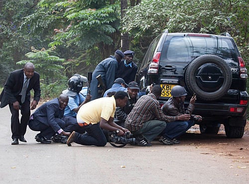 Police officers and members of the media take cover at a distance from the Westgate Shopping Centre after continuous gunfire was heard coming from the mall in Nairobi. Reuters Image