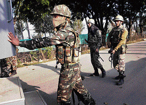 Paramilitary soldiers wait near the site of a gun-battle on the outskirts of Srinagar, on Thursday. Police said that at least seven policemen were wounded in the overnight gun-battle with suspected militants. AP