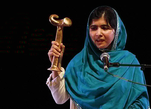 Pakistan's Malala Yousafzai waves her RAW in War Anna Politkovskaya Award while giving a speech after receiving the award at the Southbank Centre in London. Reuters