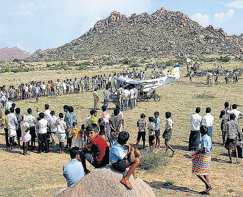 Residents look at the aircraft that made an emergency landing at Kurugodu in Bellary district on Monday.  KPN