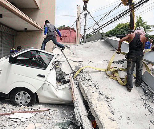 Workers use a crane to lift up concrete block that fell on a car after buildings collapsed during an earthquake in Cebu city, central Philippines October 15, 2013. At least six people were killed when buildings collapsed on islands popular with tourists in the central Philippines on Tuesday, radio reports said, after an earthquake measuring 7.2 hit the region. REUTERS