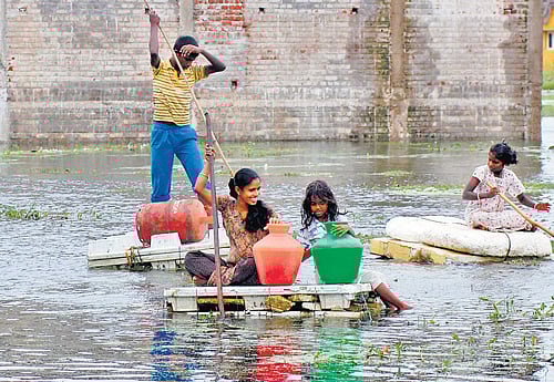 Troubled waters: People shift to safe places from a flooded locality on the outskirts of Chennai after heavy rain on Monday. PTI