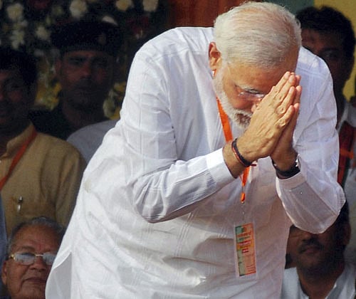Gujarat CM and BJP's Prime Ministerial candidate Narendra Modi (In Pic) greets public during his election campaign rally. Modi today attacked Rahul Gandhi for saying that ISI was in touch with Muslim youth of Uttar Pradesh's Muzaffarnagar. PTI File Photo