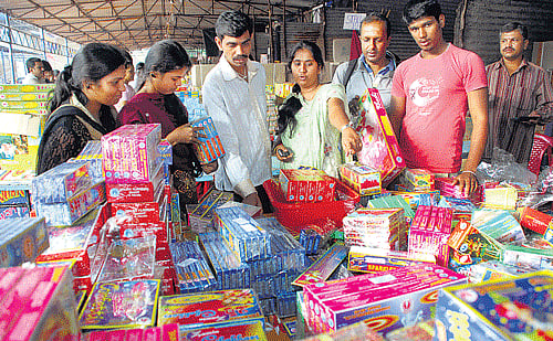 Festive spirit: People purchase crackers at Rajajinagar. (Below) Women buy lamps at a shop in Gandhi Bazaar ahead of Deepavali on Thursday. DH photos