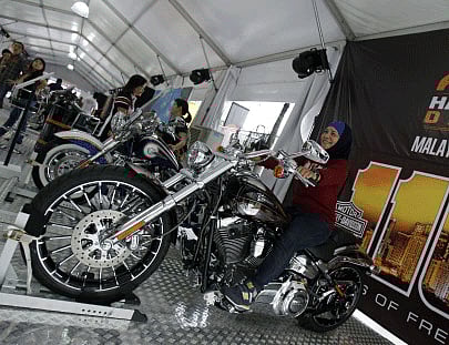 A woman sits on a Harley-Davidson CVO Breakout motorcycle as she poses for a photo during Asia Harley Days in conjunction with Harley-Davidson's global 110th anniversary celebrations in Kuala Lumpur, Malaysia, Sunday, Sept. 15, 2013. AP photo