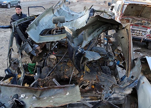 An Iraqi man inspects a bus damaged in a car bomb attack in Baghdad, Iraq, Monday, Dec. 16, 2013. AP