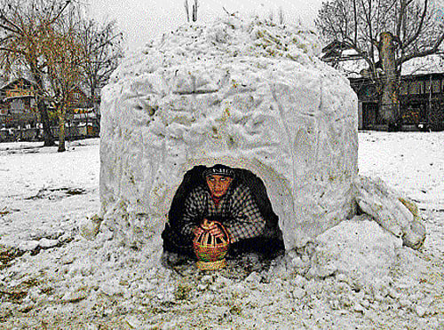 A boy sitting inside an igloo after heavy snowfall in Srinagar on Sunday. PTI