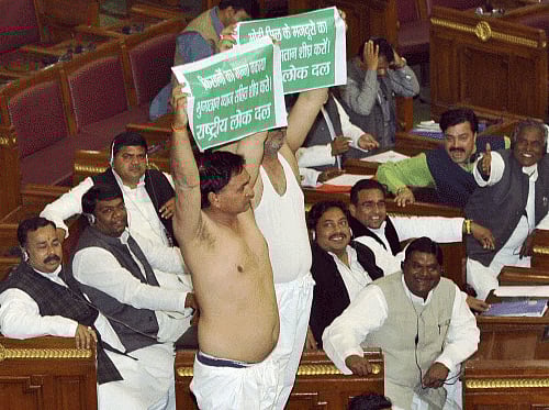 Two RLD members display placards after removing their 'kurtas' in a protest against the ruling SP government over non-payment of prices to the sugarcane farmers, during governor's address to the joint session in Lucknow on Wednesday. PTI Photo