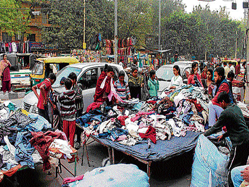 Vendors park their three-wheelers on the sidewalk, forcing people to walk on the main road after sunset. DH Photo