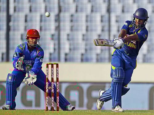 Sri Lanka's Kumar Sangakkara, right, plays a shot as Afghanistan's Mohammad Shahzad watches during their Asia Cup one-day international cricket tournament in Dhaka, Bangladesh, Monday, March 3, 2014. (AP Photo)