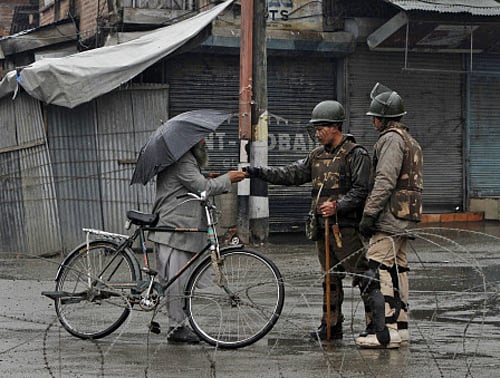 A paramilitary trooper checks the curfew pass of a Kashmiri man in Srinagar on Saturday. AP