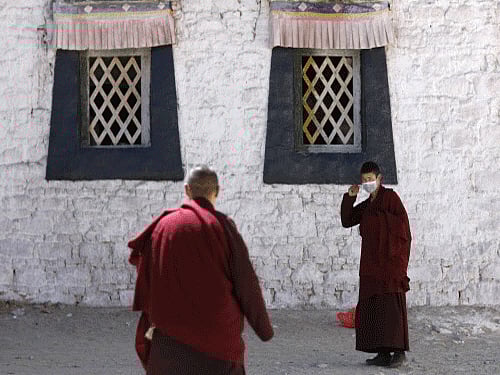 A monk wearing a mask looks on at the Samye Monastery, in Shannan Prefecture in Tibet. A Tibetan Buddhist monk today set himself on fire in China's northwest Qinghai province which has witnessed a spate of self-immolation incidents in the recent past. Reuters Photo