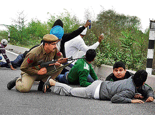 taking cover: Security officers and civilians take cover on the Jammu-Pathankot highway during a gunbattle in Kathua district of Jammu and Kashmir on Friday. AP